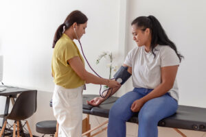 Woman having blood pressure measured by primary care doctor